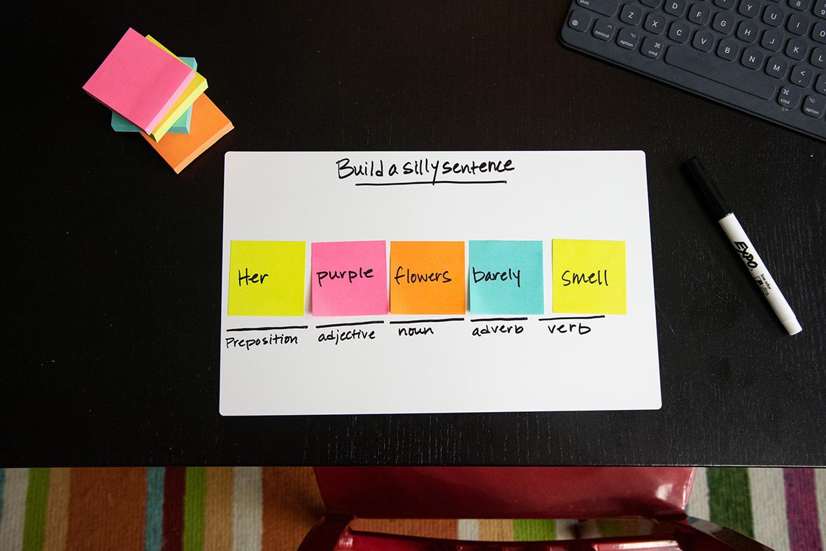 Post-it notisbok med rosa, orange, gul och lila lappar på svart skrivbord