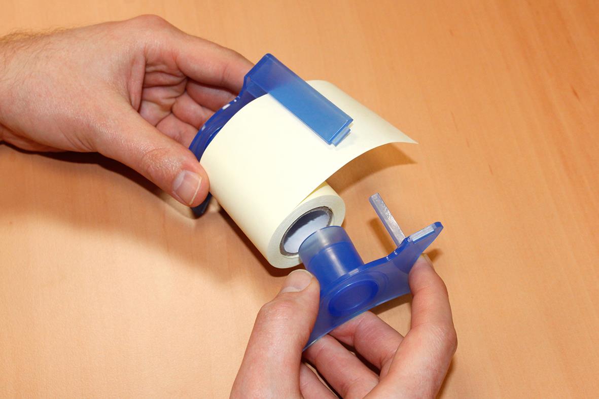 Person håller i en gul notisremsa med blå dispenser för att skriva eller märka