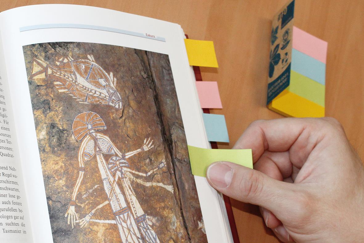 Person använder färgade flikar för att markera sidor i en bok eller katalog