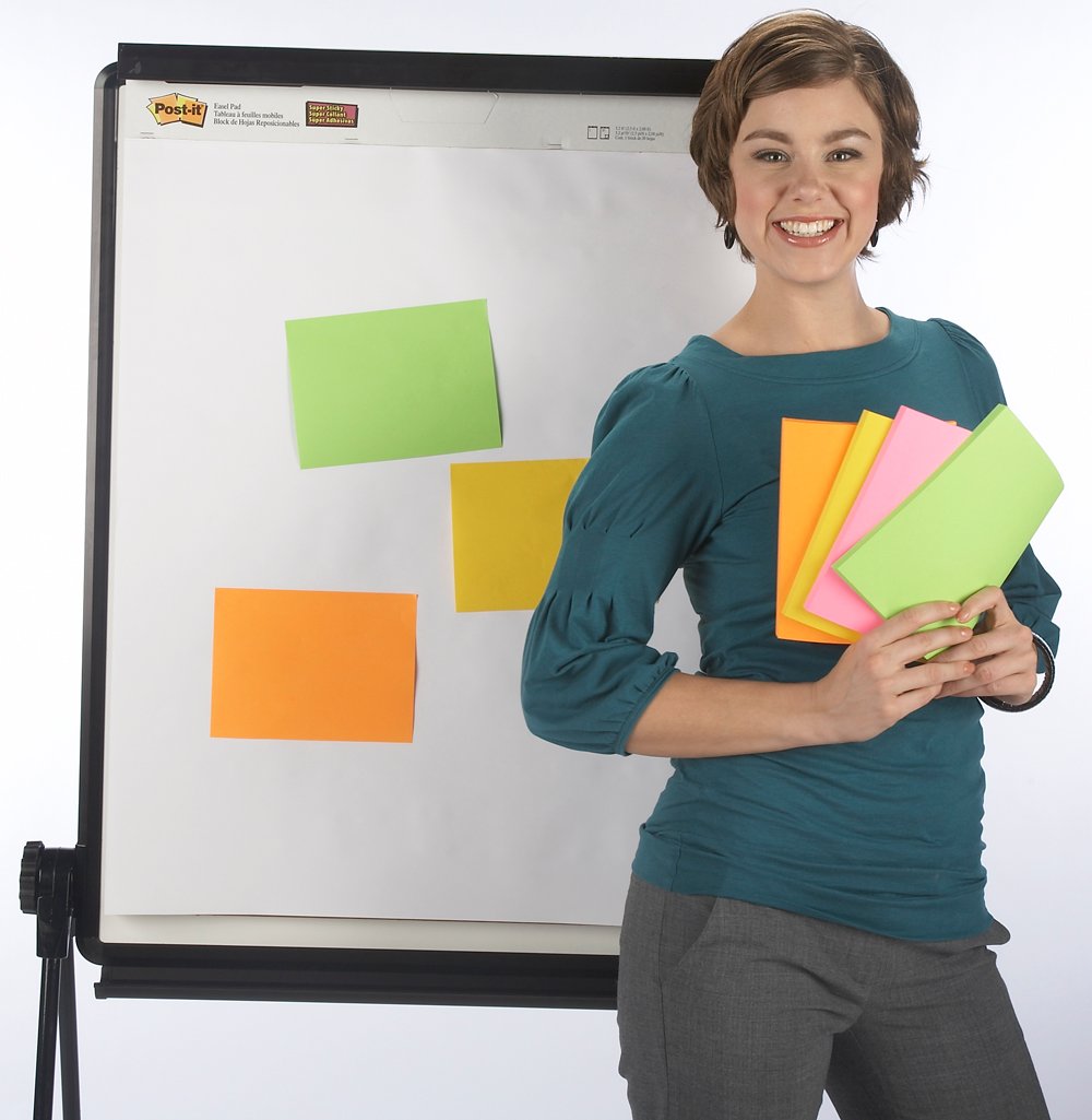 Kvinna håller färgglada Post-it lappar framför whiteboard med fler lappar fastsatta