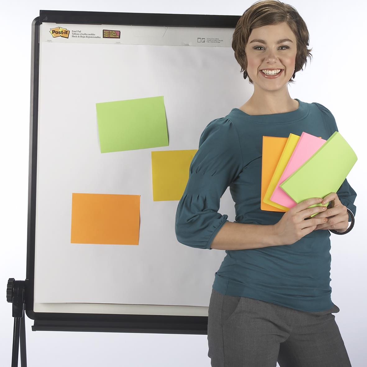 Kvinna håller färgglada Post-it lappar framför whiteboard med fler lappar fastsatta