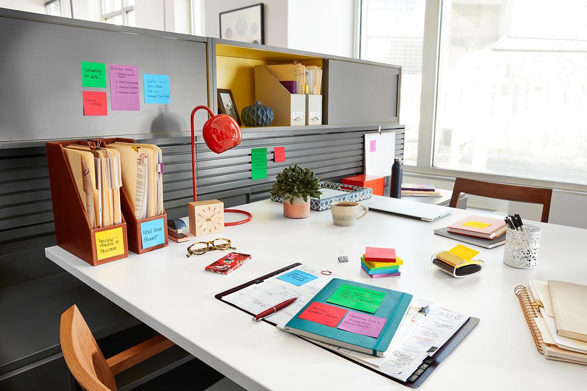 Kontorsbord med Post-it lappar, mappar, växt och kontorsmaterial i ett arbetsrum