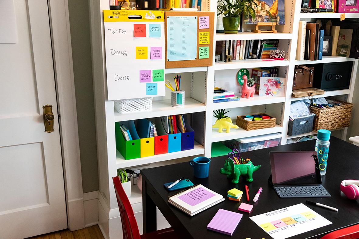 Organiserat hemmakontor med whiteboard, färgglada Post-it lappar, skrivbord med laptop, pennor och kontorsmaterial