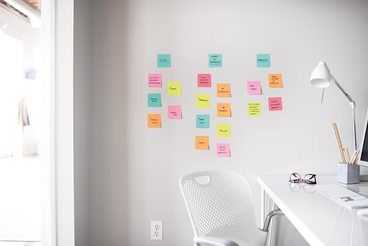 Flera färgglada Post-it lappar på en vit vägg i ett kontorsutrymme