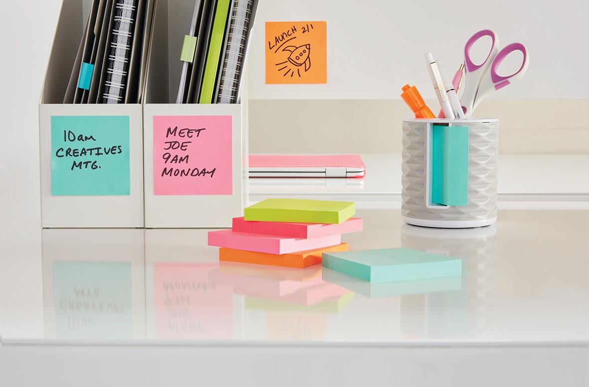 Post-it lappar i olika färger på skrivbord med pennor och anteckningar