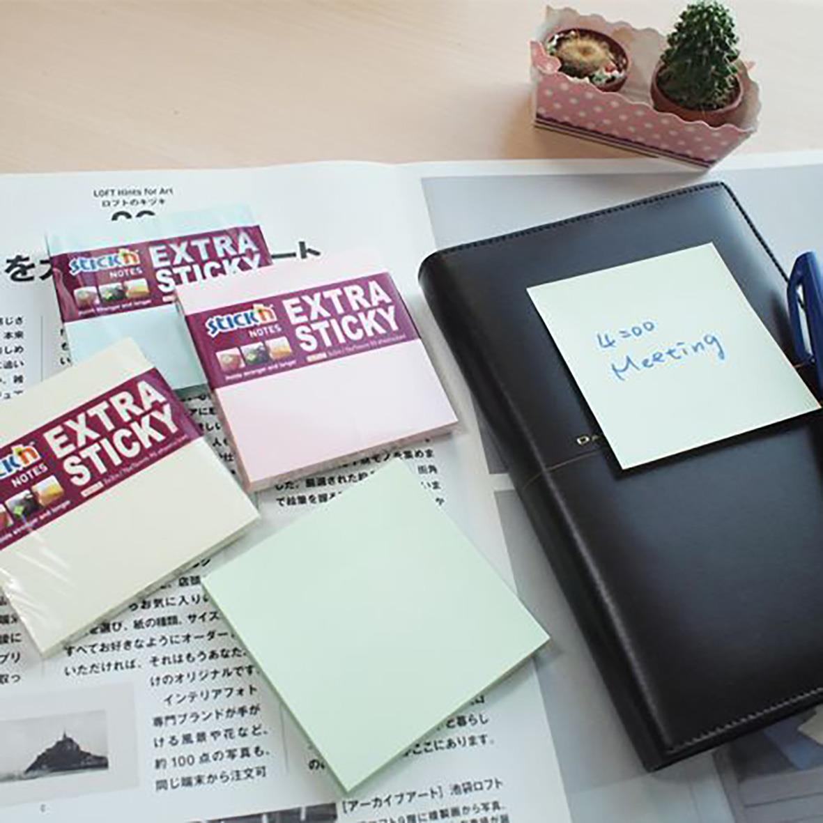 Notisar Stick'n Extra Sticky Pastell 76x76mm 100 blad på skrivbord med anteckningsblock och växt