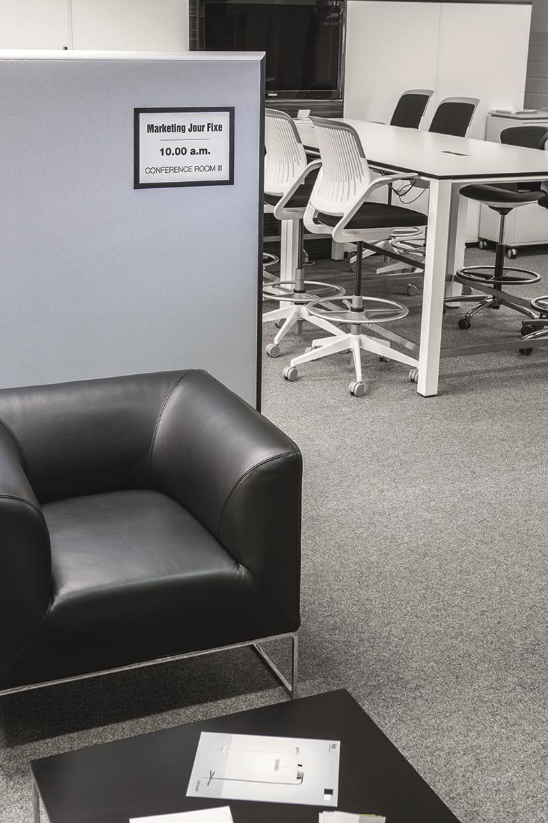 Svart Duraframe grip A4 informationsskylt i kontorsmiljö med konferensrum och möbler