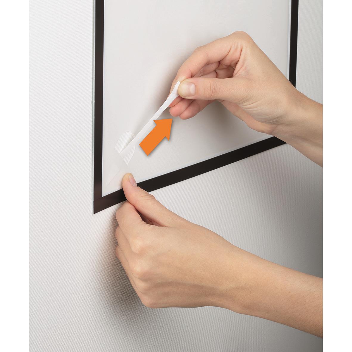 Person som applicerar svart Duraframe-väggpapper på en vägg med hjälp av en spatel