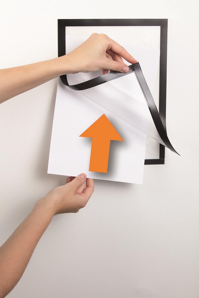 Person som sätter upp svart Duraframe väggram med svart tejp på en vit vägg, visar hur man fäster en A4-size poster