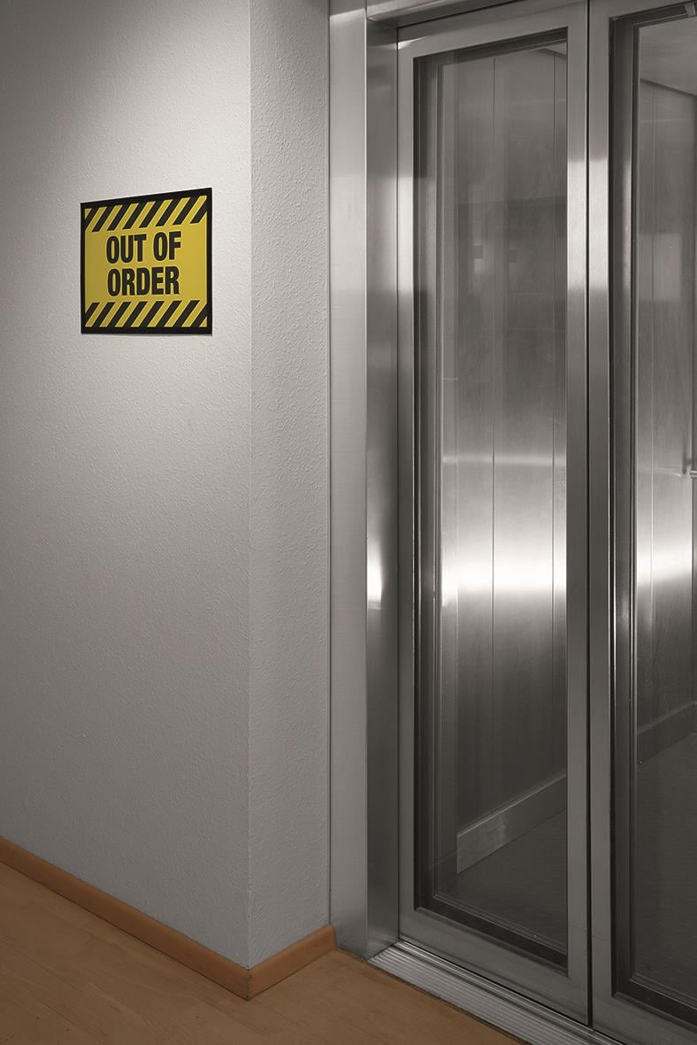 Vägg med utgången är utanför beställning skylt bredvid en hissdörr i metall
