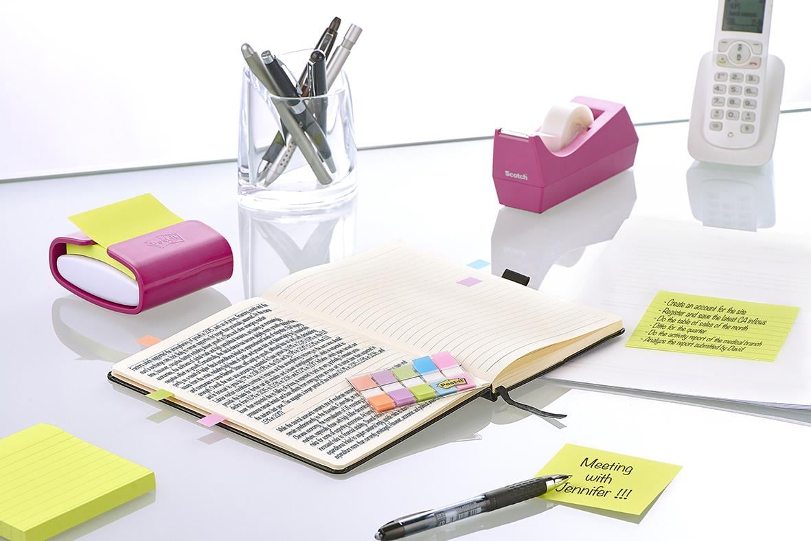 Kontorsbord med Post-it flikar, pennor, telefon och anteckningar