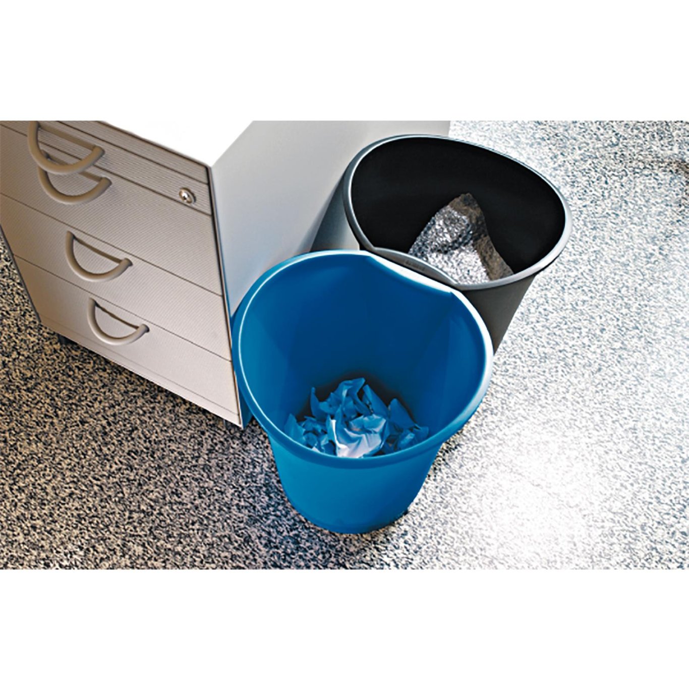 Två papperskorgar, en svart och en blå, placerade bredvid en vit skrivbordslåda