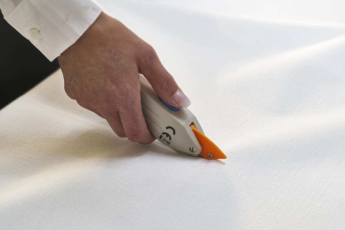 Person använder en batterisax för att klippa i en dukrulle