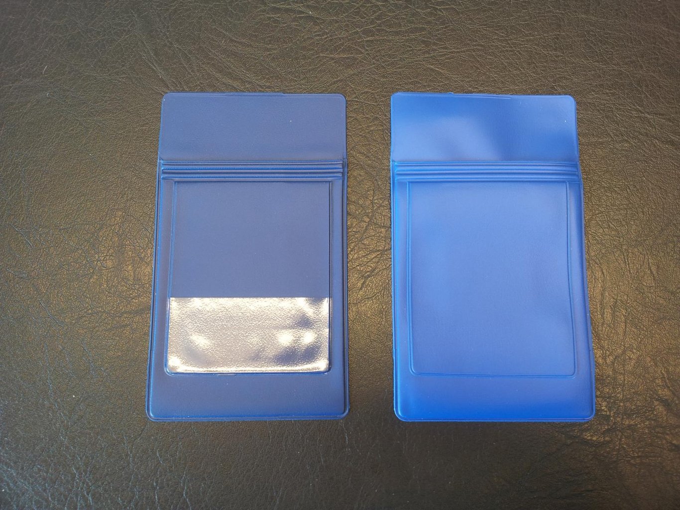 Två blå pennfickor för skyddsrockar, en med transparent fönster