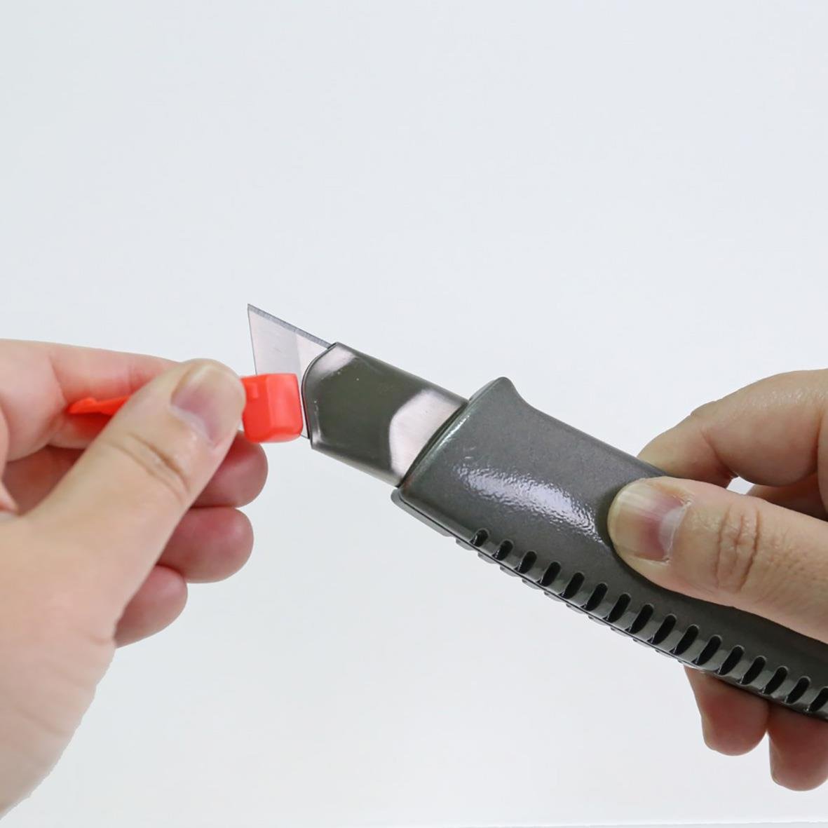 Person som håller en stålförstärkt brytbladskniv NT-Cutter L-500GP med röd säkerhetslås