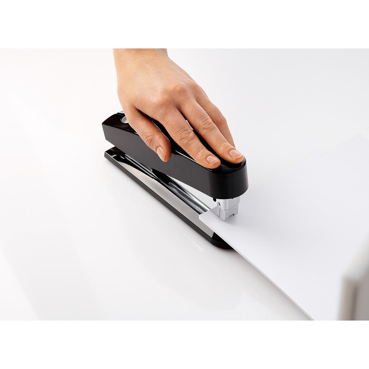 Hand som använder svart häftapparat för att häfta papper