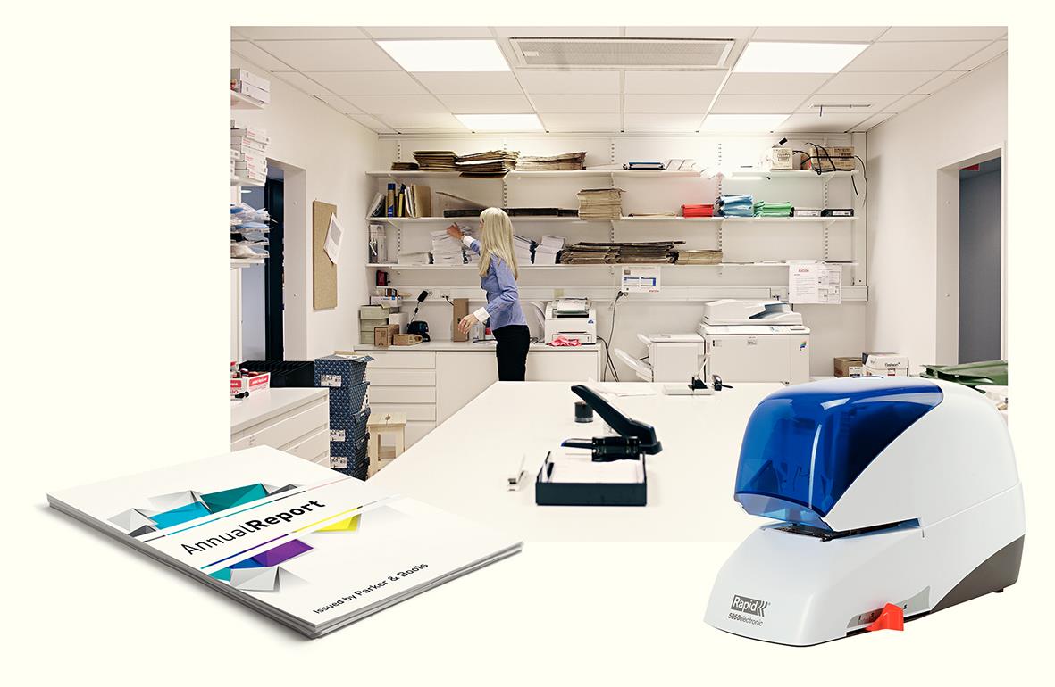 Kontorsmiljö med en person som arbetar vid skrivbord och en blå elhäftare på bordet