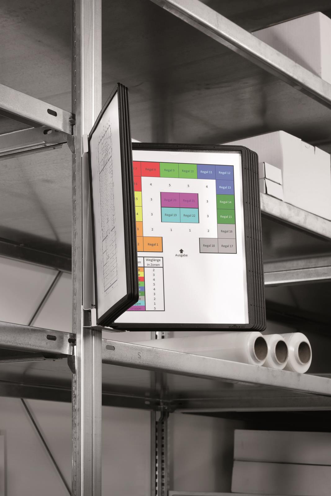 Väggpanel i svart med schematisk planritning av ett panelsystem, monterad på hylla i lager eller verkstad