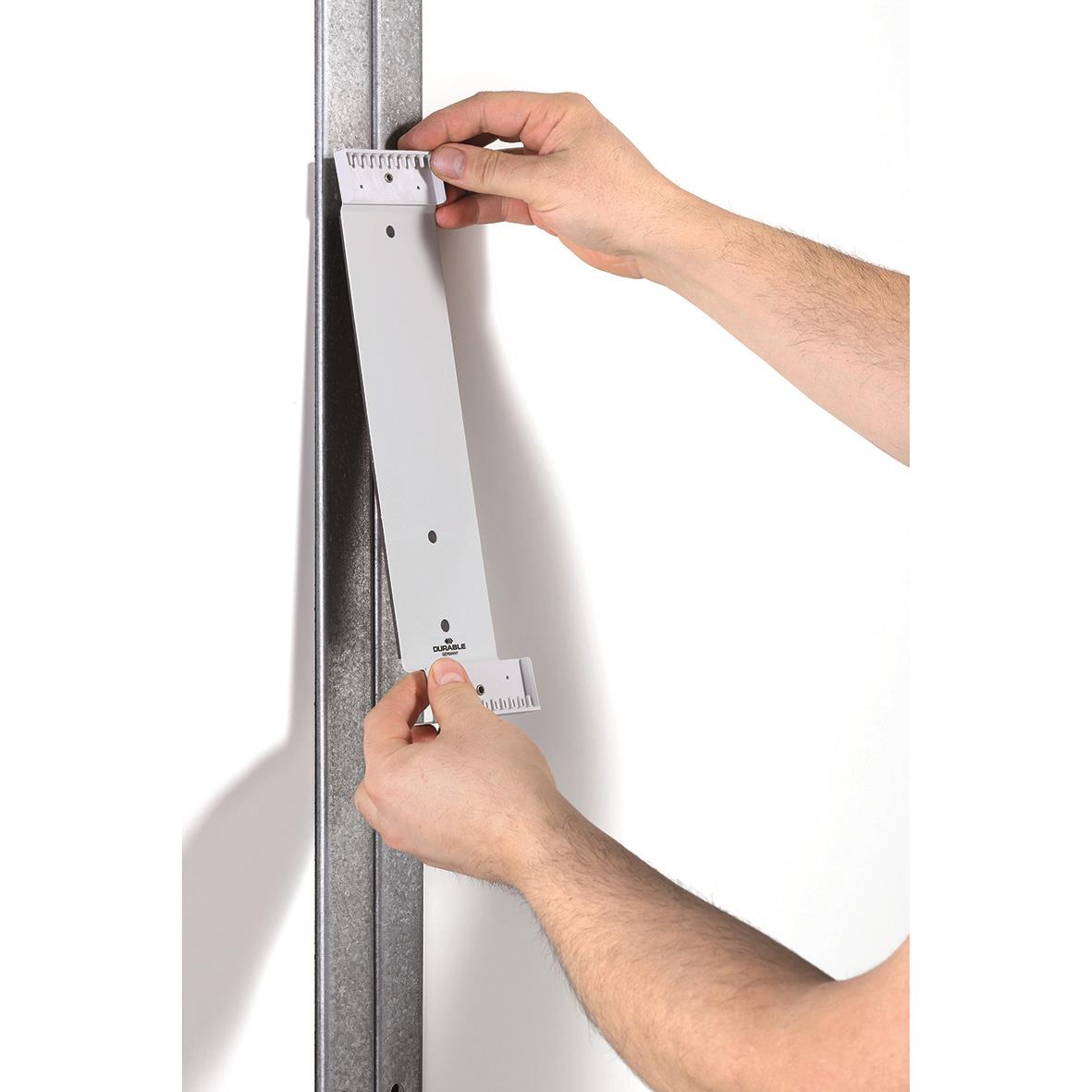 Person monterar ett svart väggpanelsystem med 10 paneler på en metallram