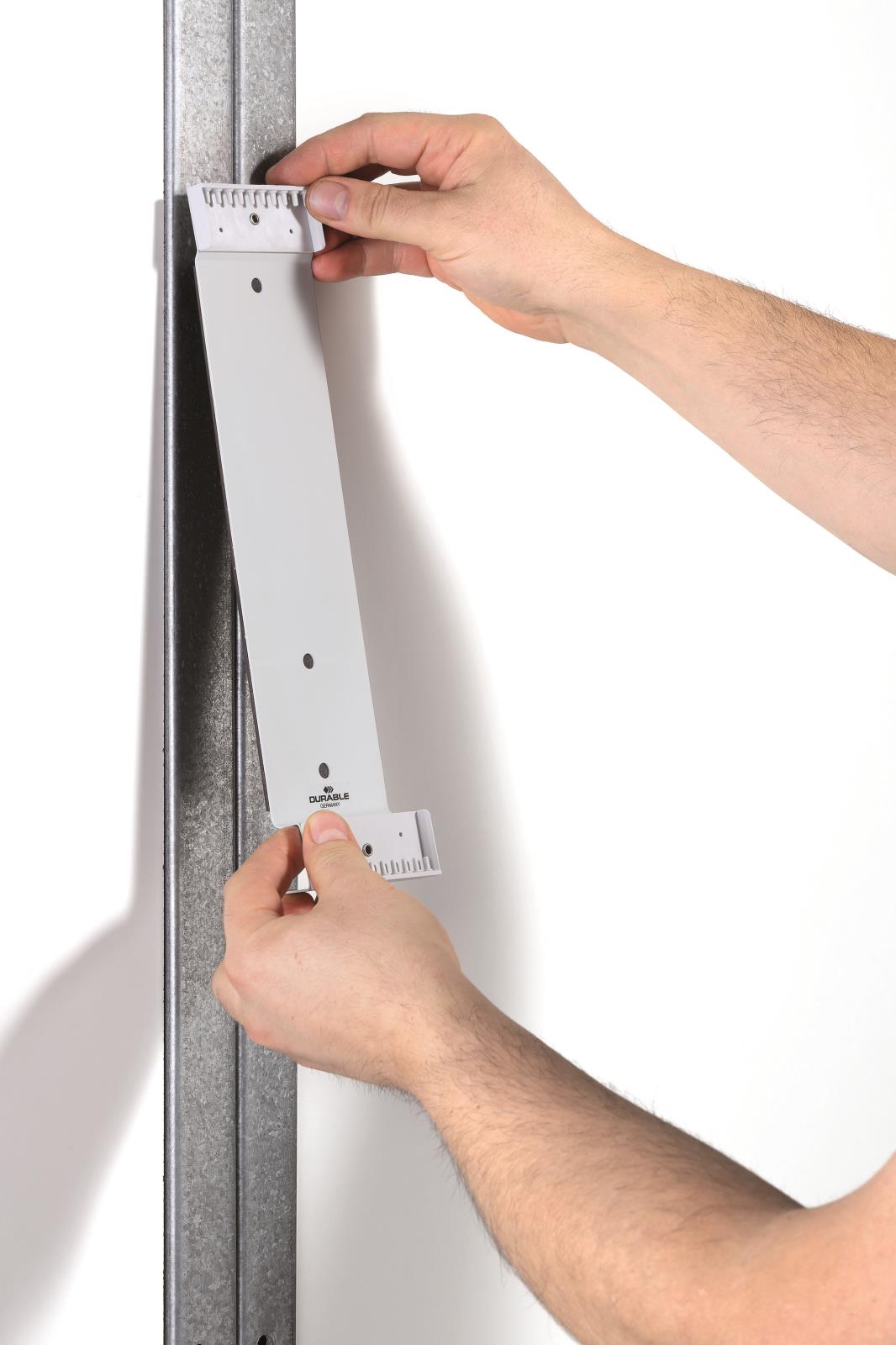 Person monterar ett svart väggpanelsystem med 10 paneler på en metallram