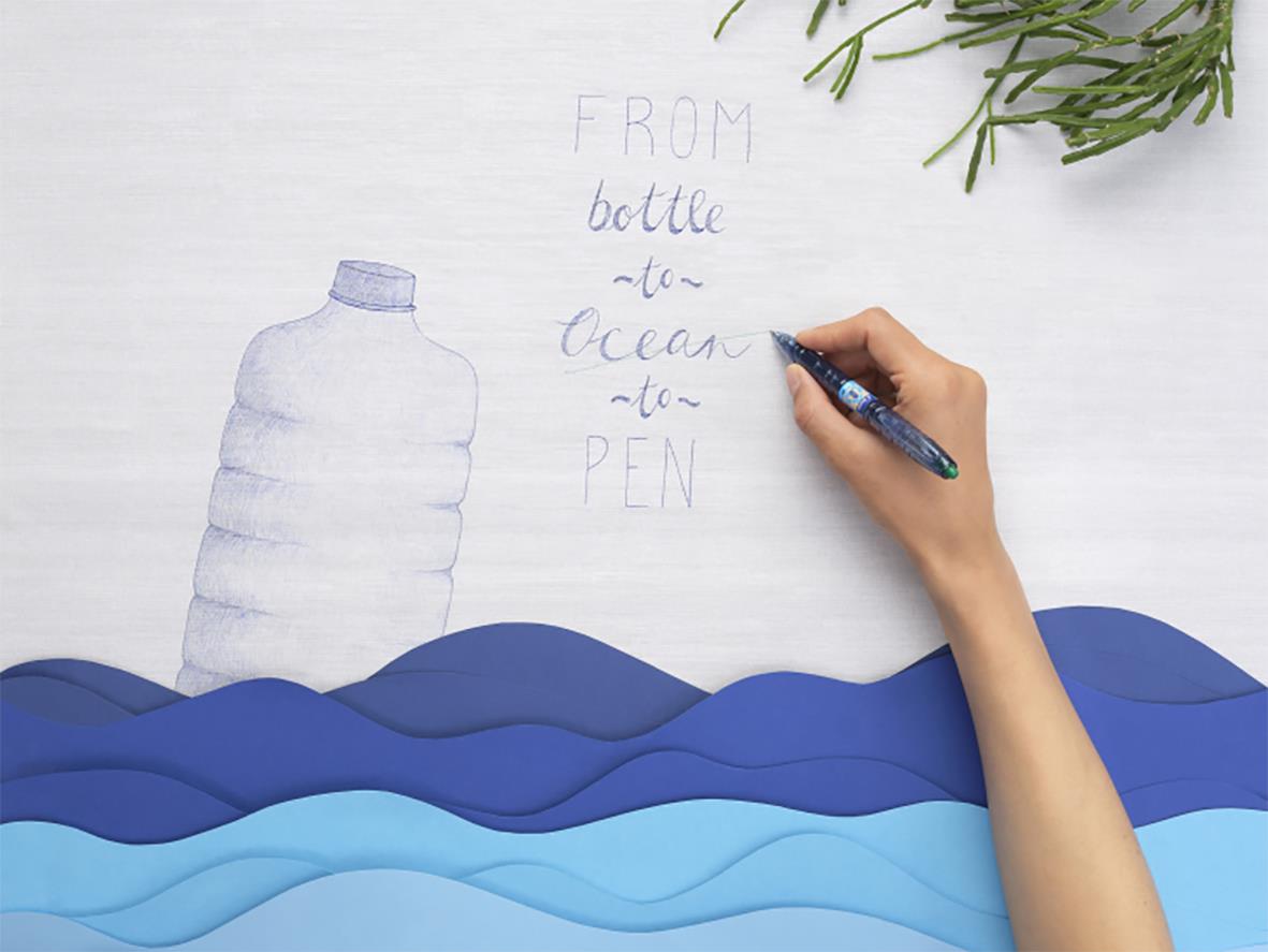 Hand som skriver på papper med en Pilot B2P Ecoball pen, tecknar en vattenflaska och havsvågor