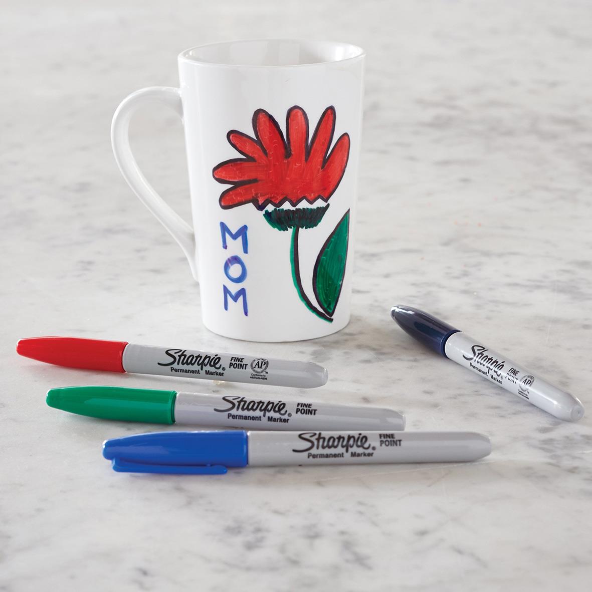 Mugg med tecknad blomma och tre Sharpie permanentpennor i rött, grönt och blått