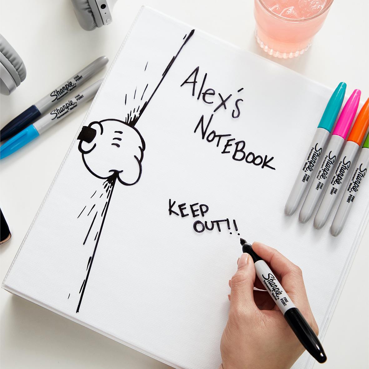 Skiss av en hunds ansikte och texten Alexis Notebook med Sharpie-märken i fyra färger