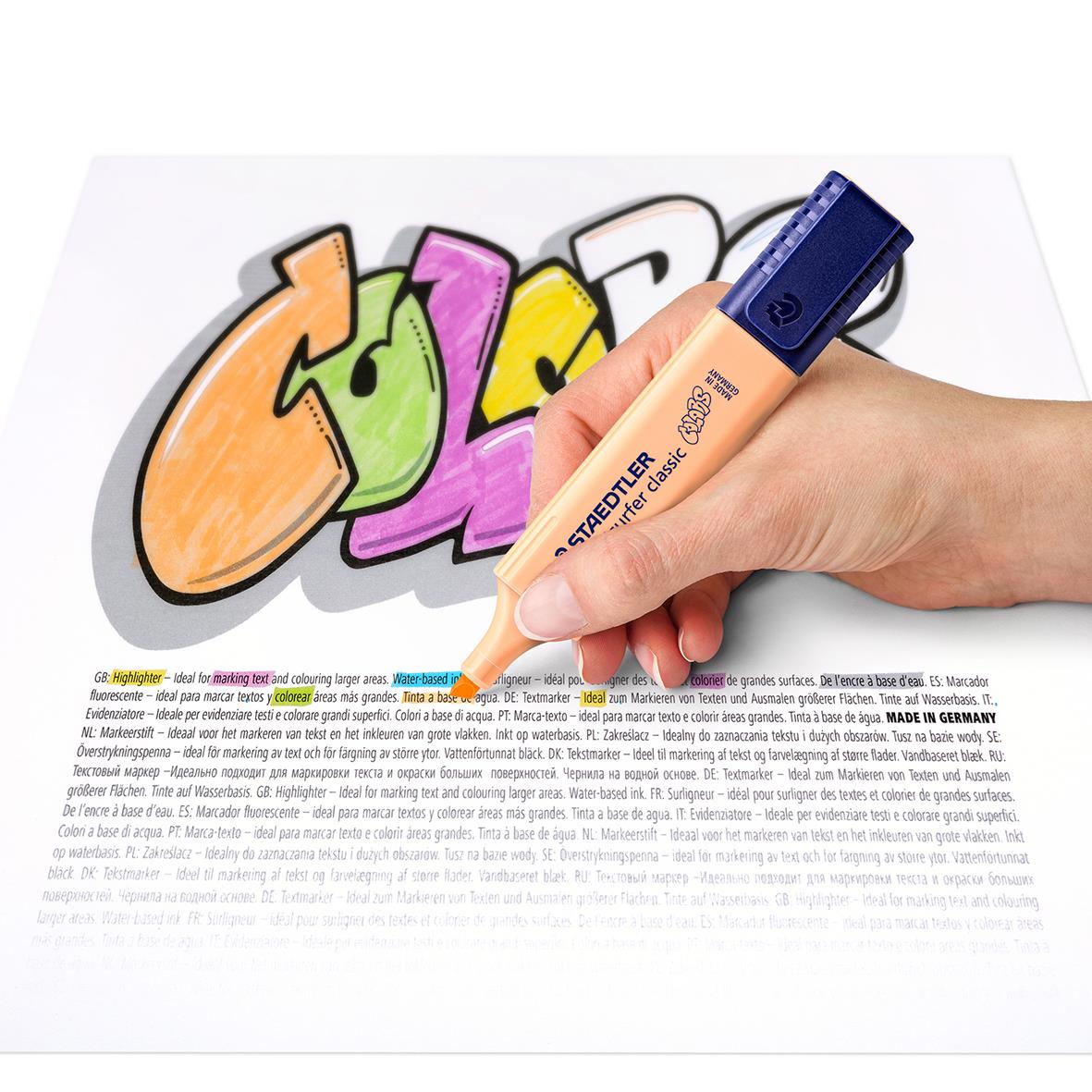 Hand som använder en Staedtler Textsurfer 364 pastellmarkering på graffiti med färgglada bokstäver