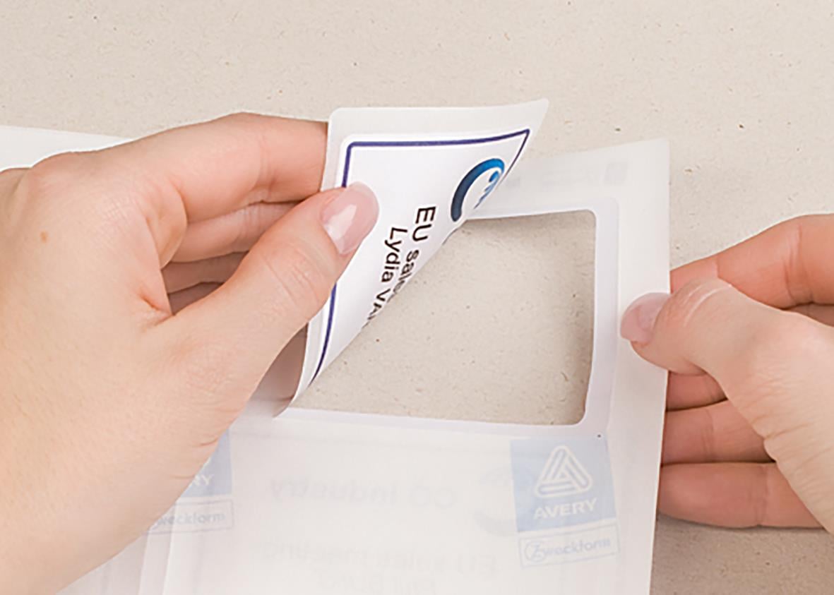 Person placerar en vit namnskylt av PVC-material i en ram på en vägg