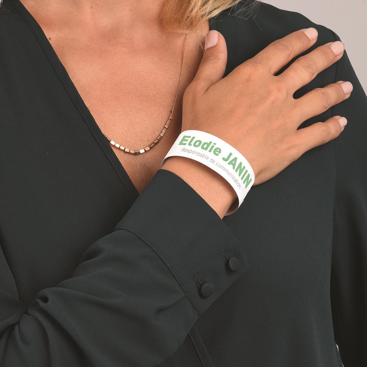Vitt handledsband med text Elodie JANIN på en persons handled