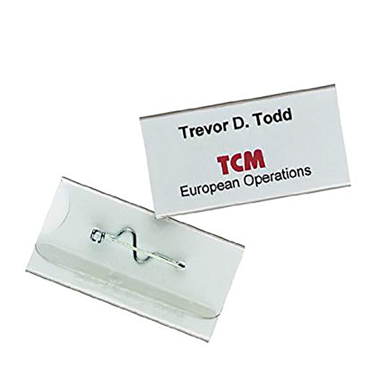 Namnskylt av hållbart material med nål, storlek 75x40mm, visar namn Trevor D. Todd och organisationen TCM European Operations
