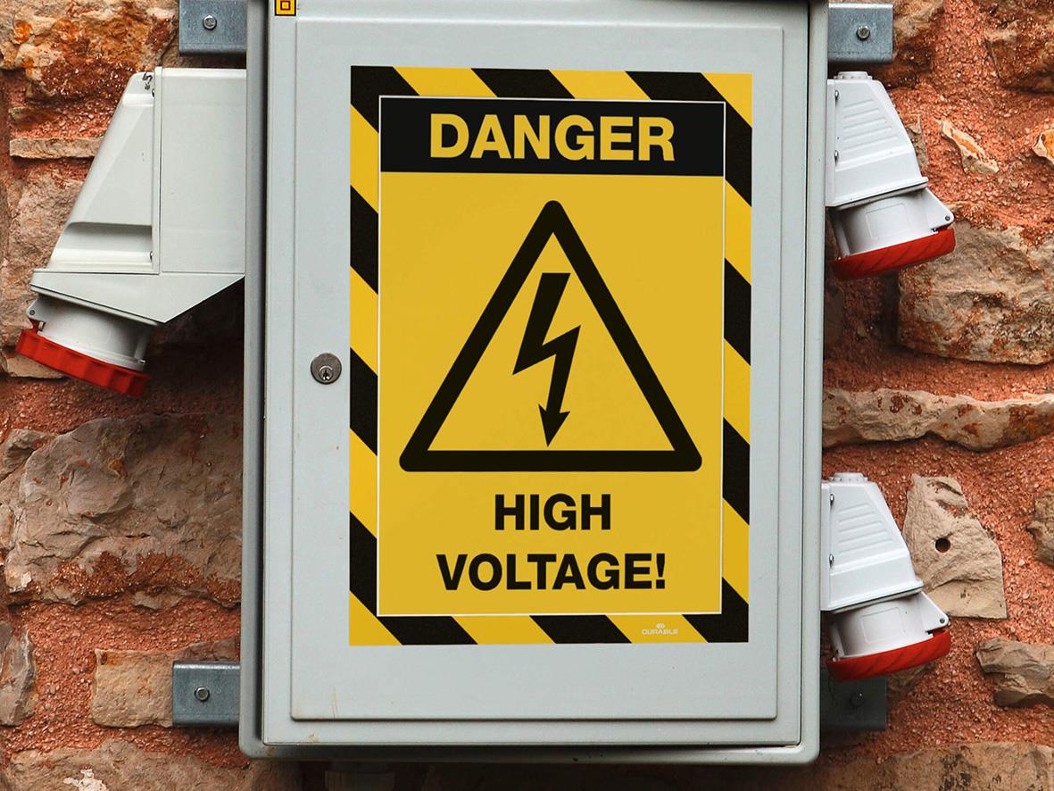 Elvarningsskylt med text DANGER HIGH VOLTAGE och varningssymbol på elskåp monterat på tegelvägg