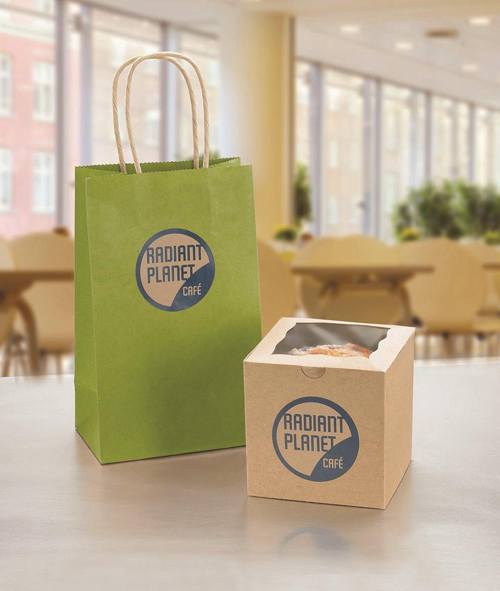 Grön papperspåse och liten kartong med Radiant Planet Café-logga på ett bord i ett ljust kafé.