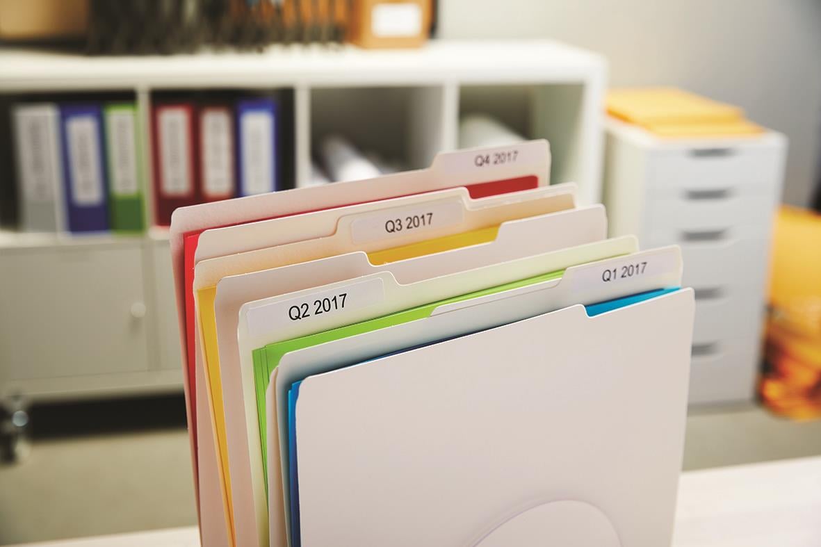 Färgglada hängmappar med etiketter i ett kontorsskåp
