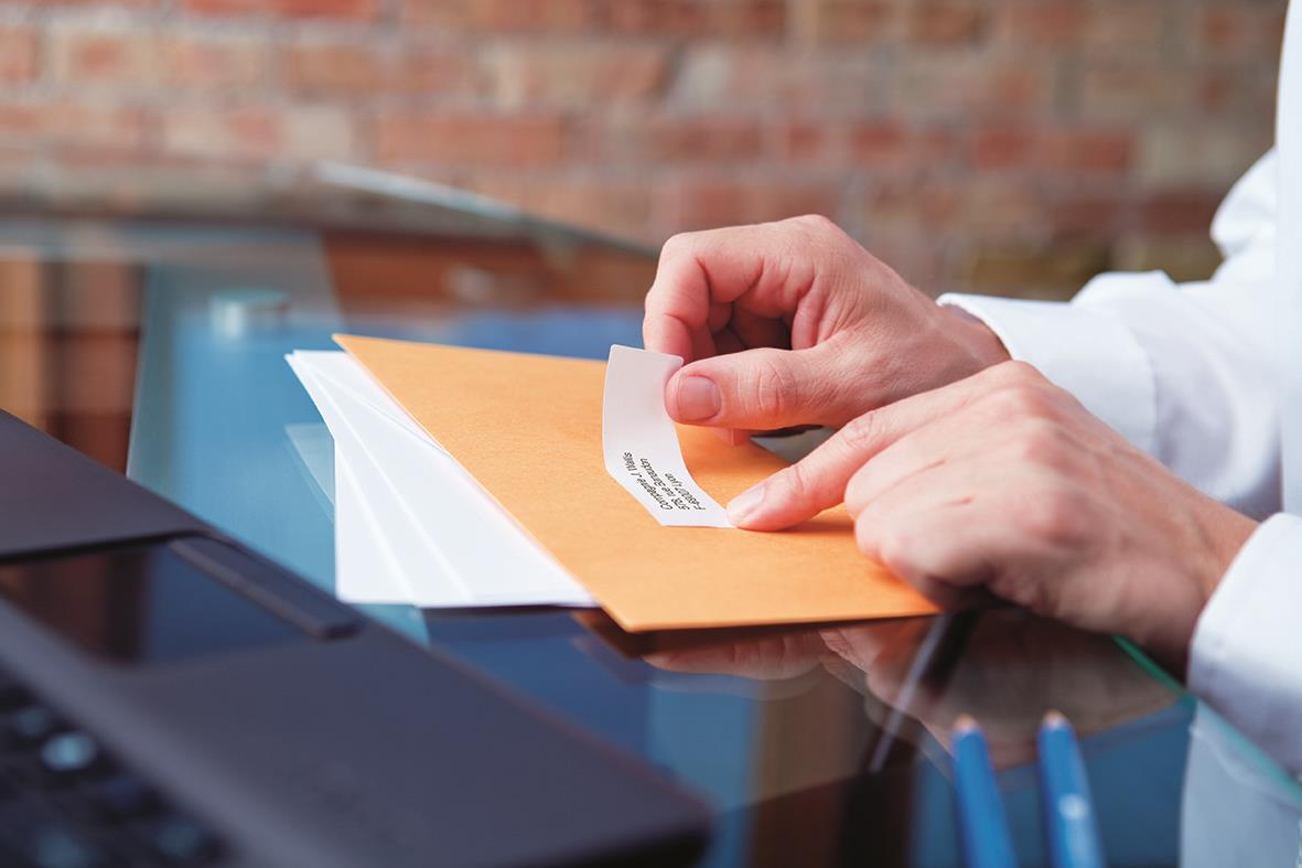 Person skriver ut en vit adressetikett på Dymo Labelwriter 25x54mm på ett skrivbord