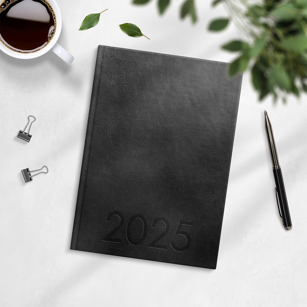 Svart 2025 års almanacka med veckoplanering i konstläder, inbunden, A5 storlek, på vit bakgrund med penna, koppar och gröna blad