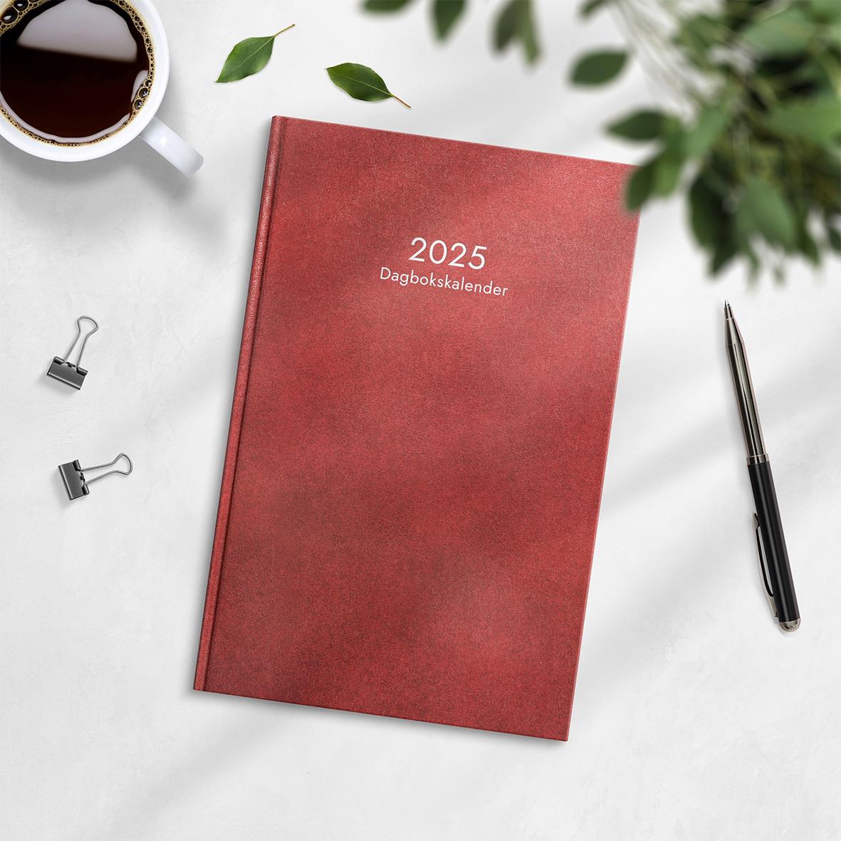 Röd inbunden dagbokskalender för 2025 med omslag och skrivmaterial runt omkring