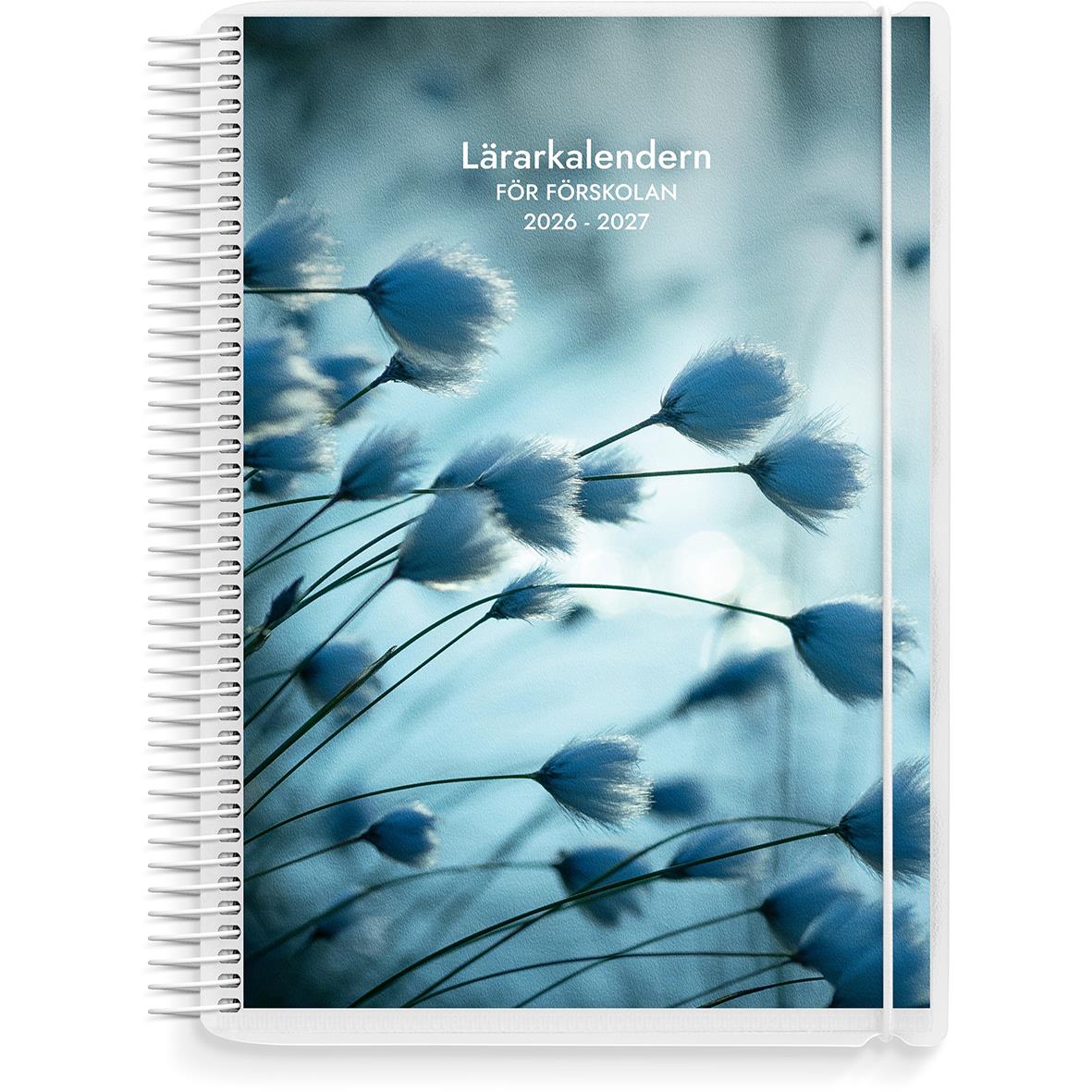 Lärarkalender för förskolan 2025-2026 med grön omslag och spiralbindning, omgiven av gröna växter, penna och klämmor