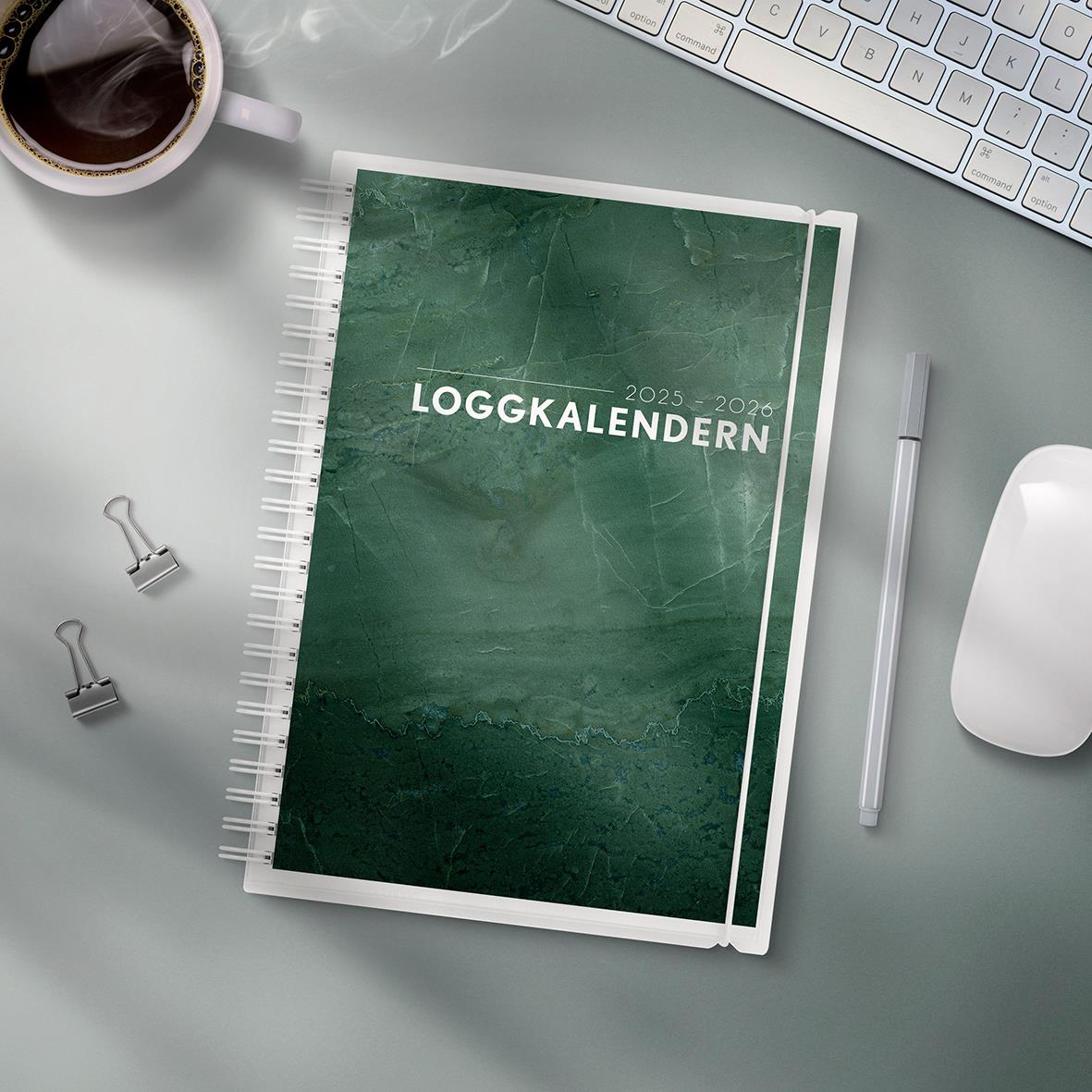 Loggkalender 2023-2024 i A5-format med grönt omslag, omgiven av kontorsmaterial och en kopp kaffe