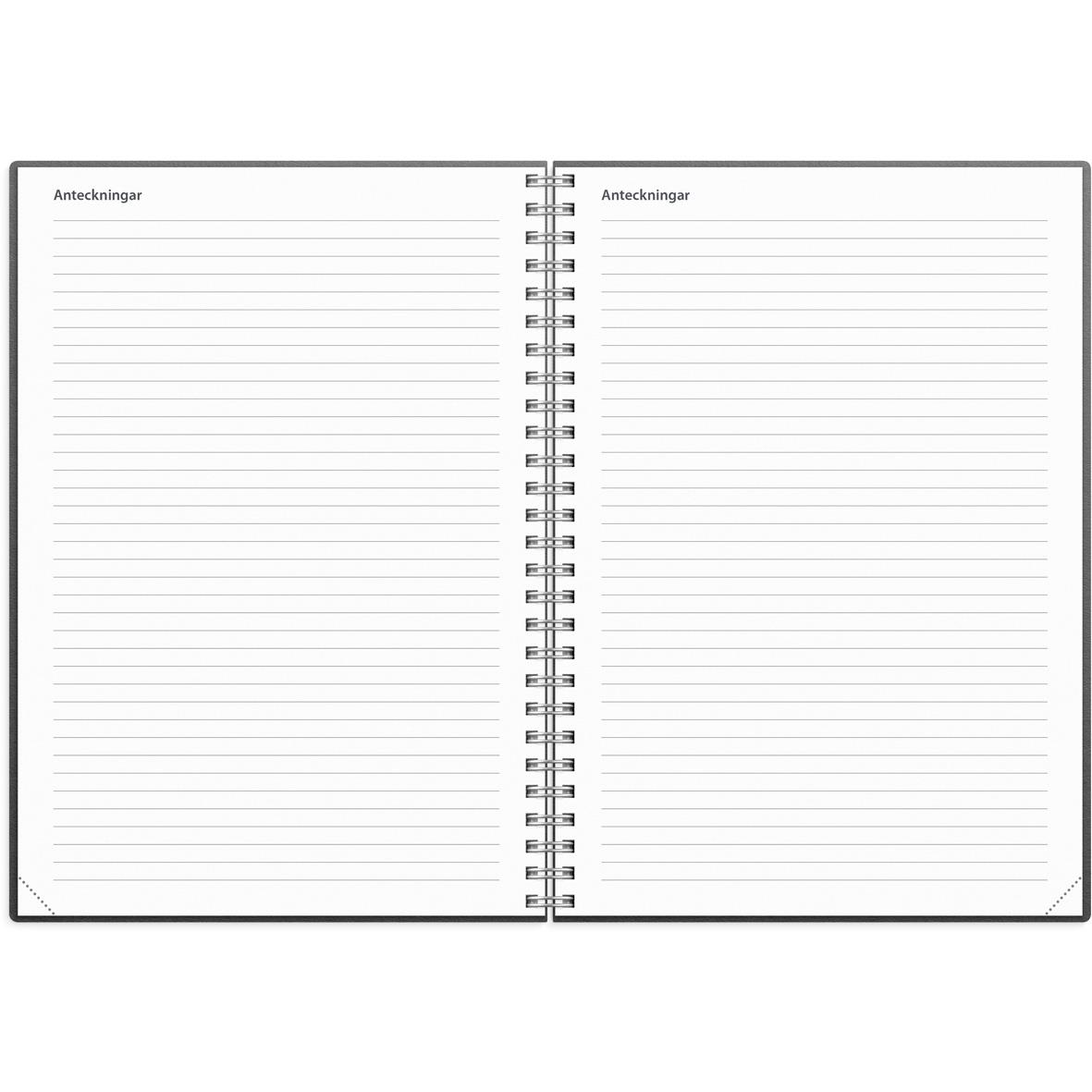 Projektkalender 2025 i svart omslag med spiralbindning, omgiven av penna, klämmor, kaffe och gröna växter