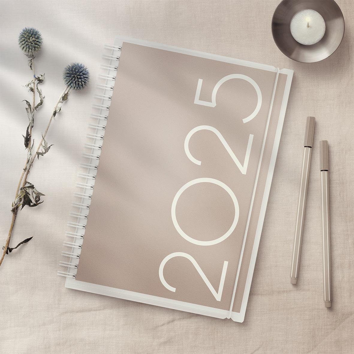 Årsplanerare för 2026 med spiralbindning och PP-omslag, liggande på ljus bakgrund med blommor, penna och ljus