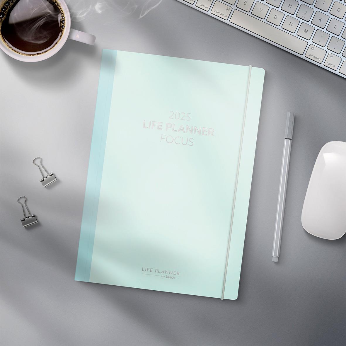 Lifplaner för 2026 med fokus, omgiven av kaffekopp, tangentbord, mus och penn på ett skrivbord