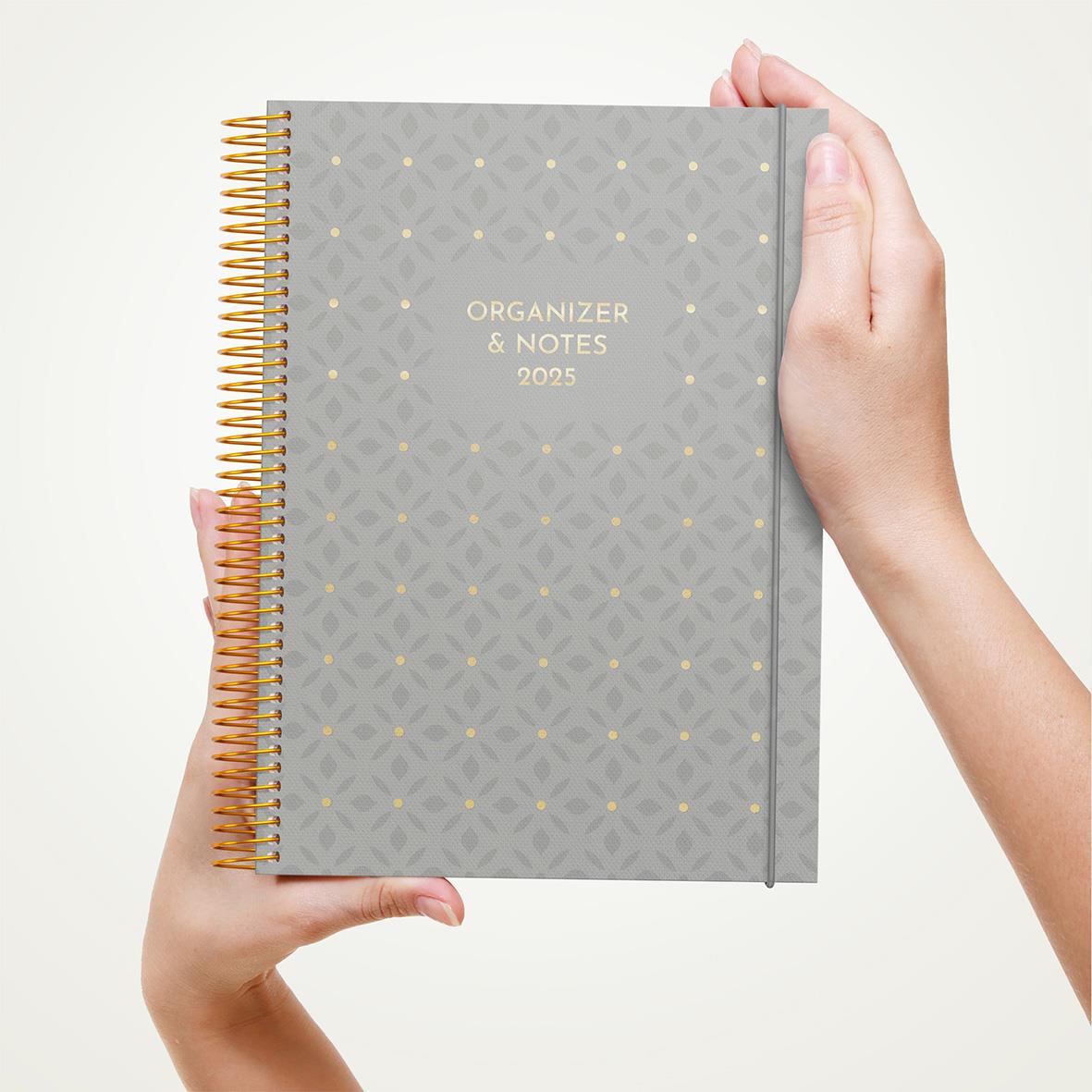 Grå almanacka med guldtext och spiralrygg, används för organisering och anteckningar 2026
