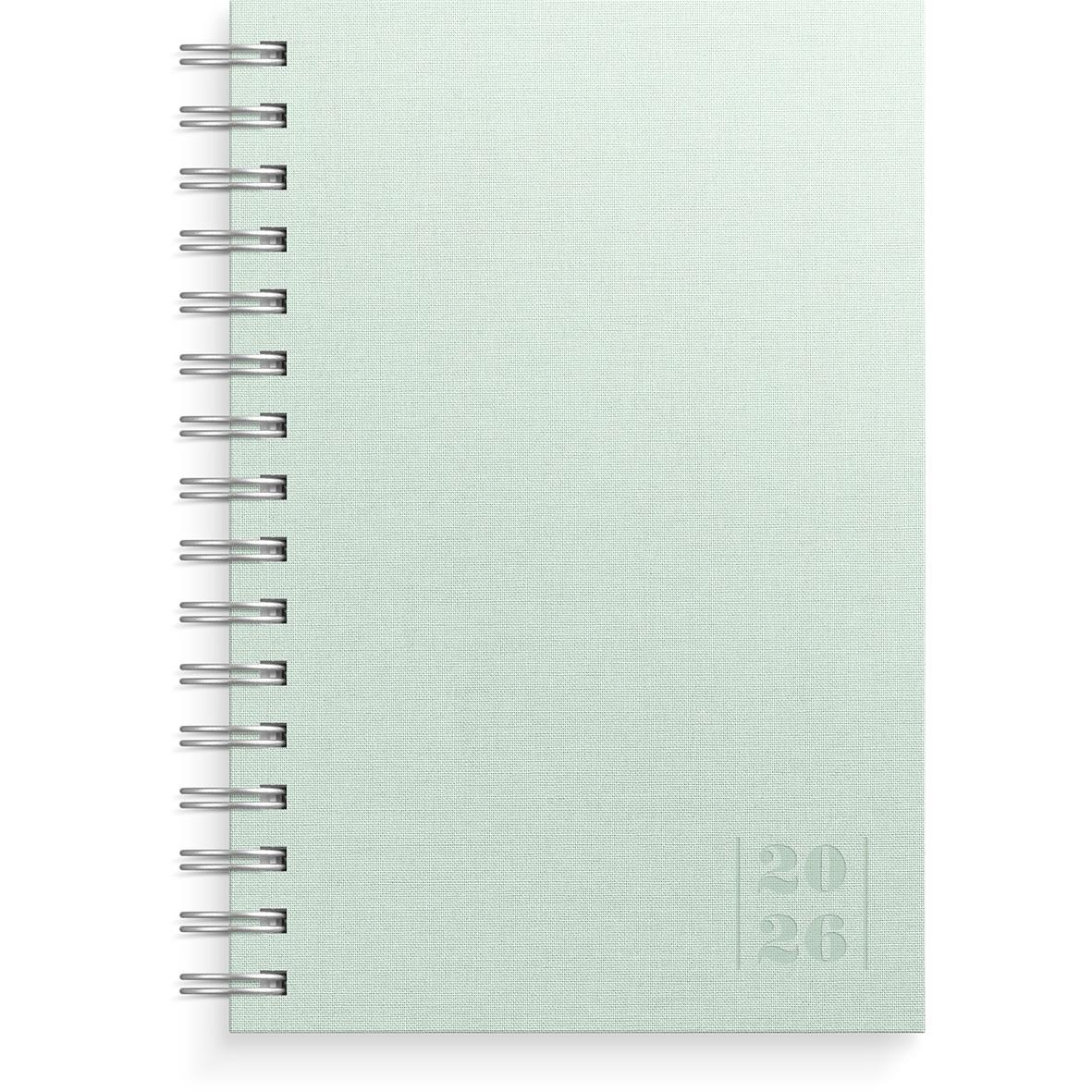 Grön textildagbok för 2026 med spiralrygg och årtal på framsidan