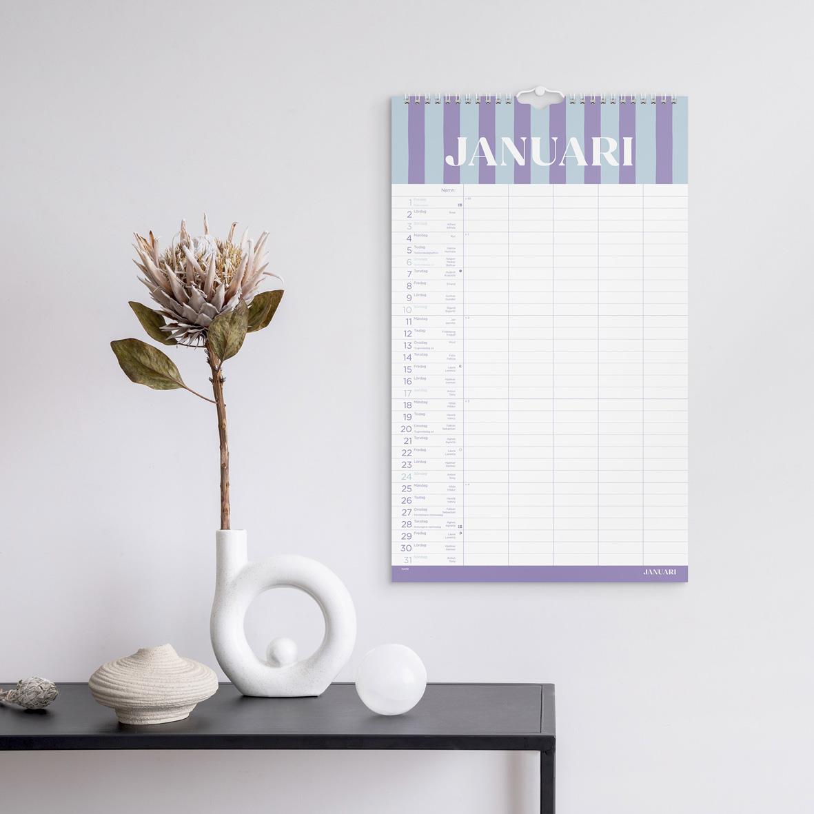 Familjekalender för januari 2027 med färgblockering och blomsterdekoration på svart bord