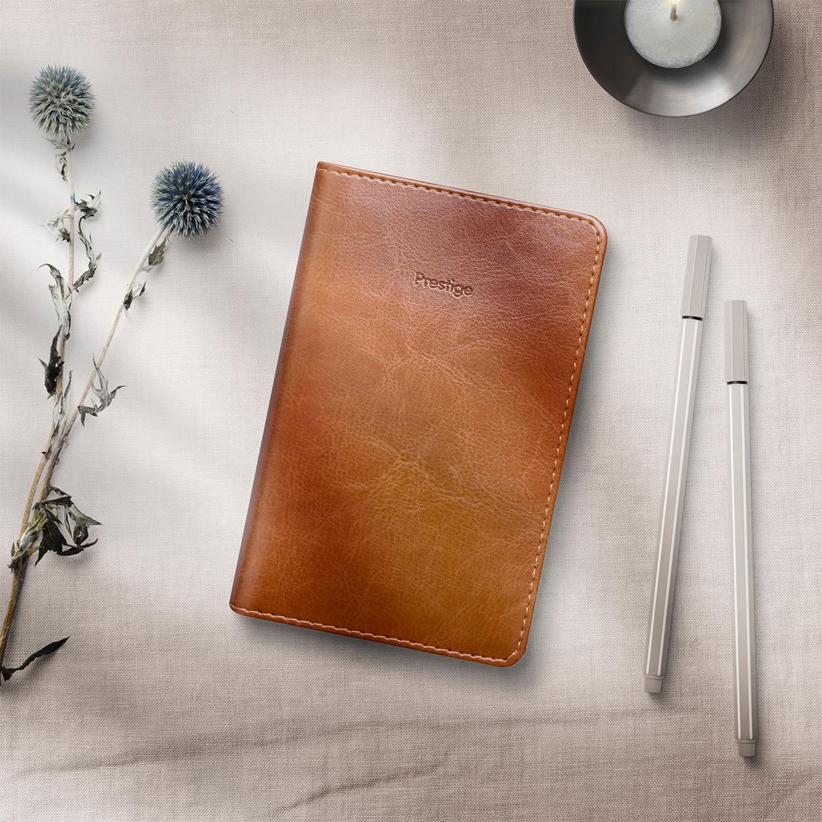 Brun konstläderalmanacka Prestige Burde 2026 Cognac med två vita pennor på ljus bakgrund