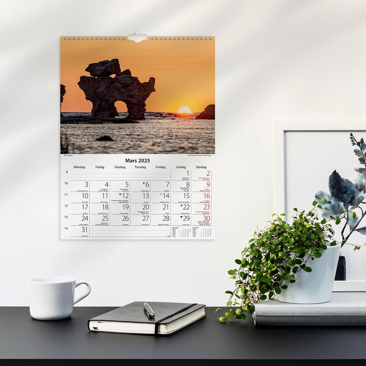 Väggkalender med bild av en stenformation vid kusten vid solnedgång, mars 2025