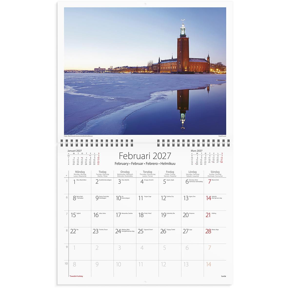 Väggkalender för december 2025 med bild av Stockholm vid vattnet, på en vit vägg bredvid en grön växt