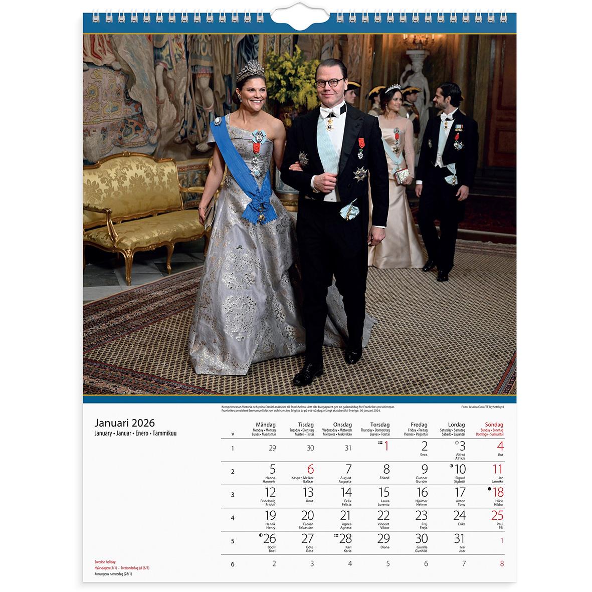 Väggkalender för 2026 med Kungafamiljen i formell klädsel, inomhusmiljö, gul soffa och konst på väggarna