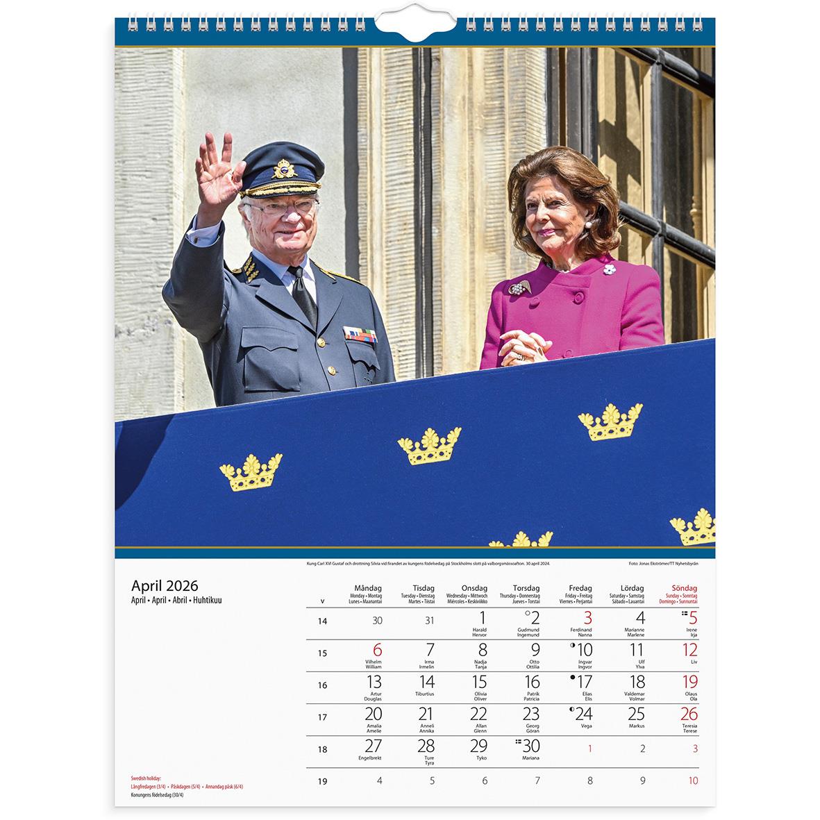 Väggkalender för 2026 med Kungafamiljen, visar en man i militäruniform och en kvinna i rosa, bakom en blå skylt med kungakronor.
